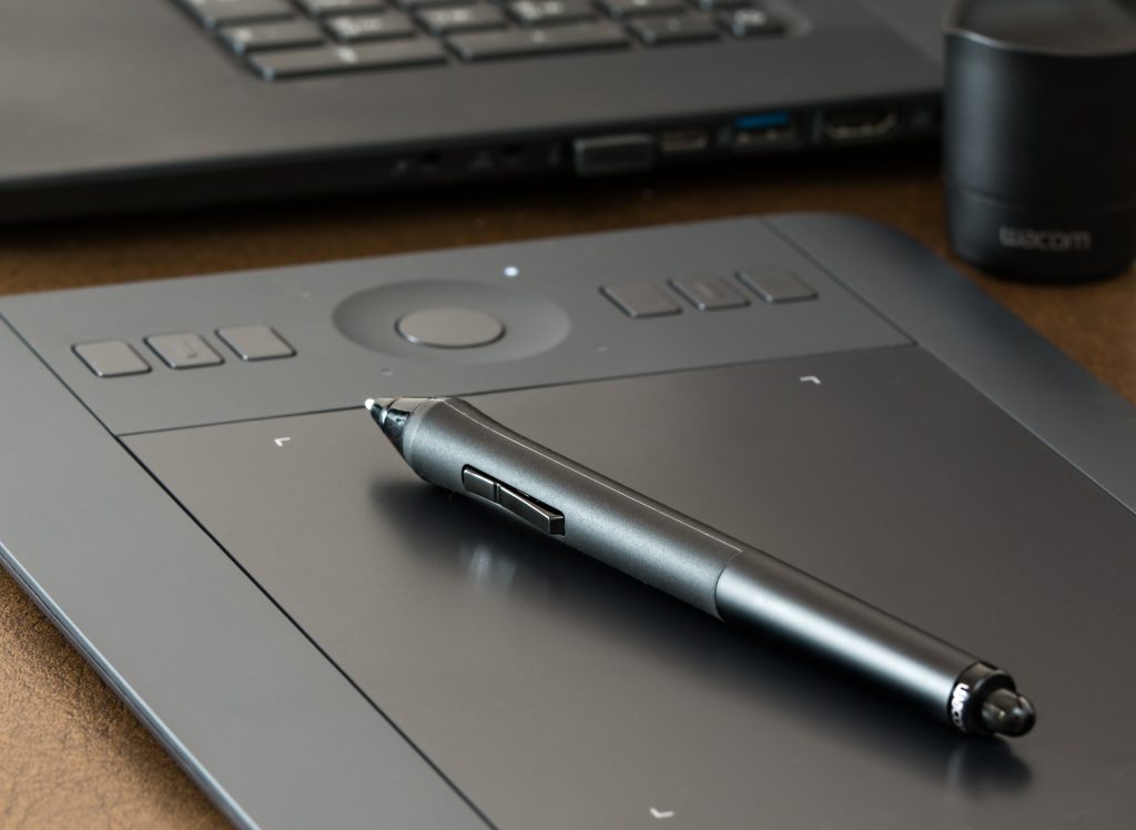 An image of a black digital daring pad with a black digital pen lying on top.